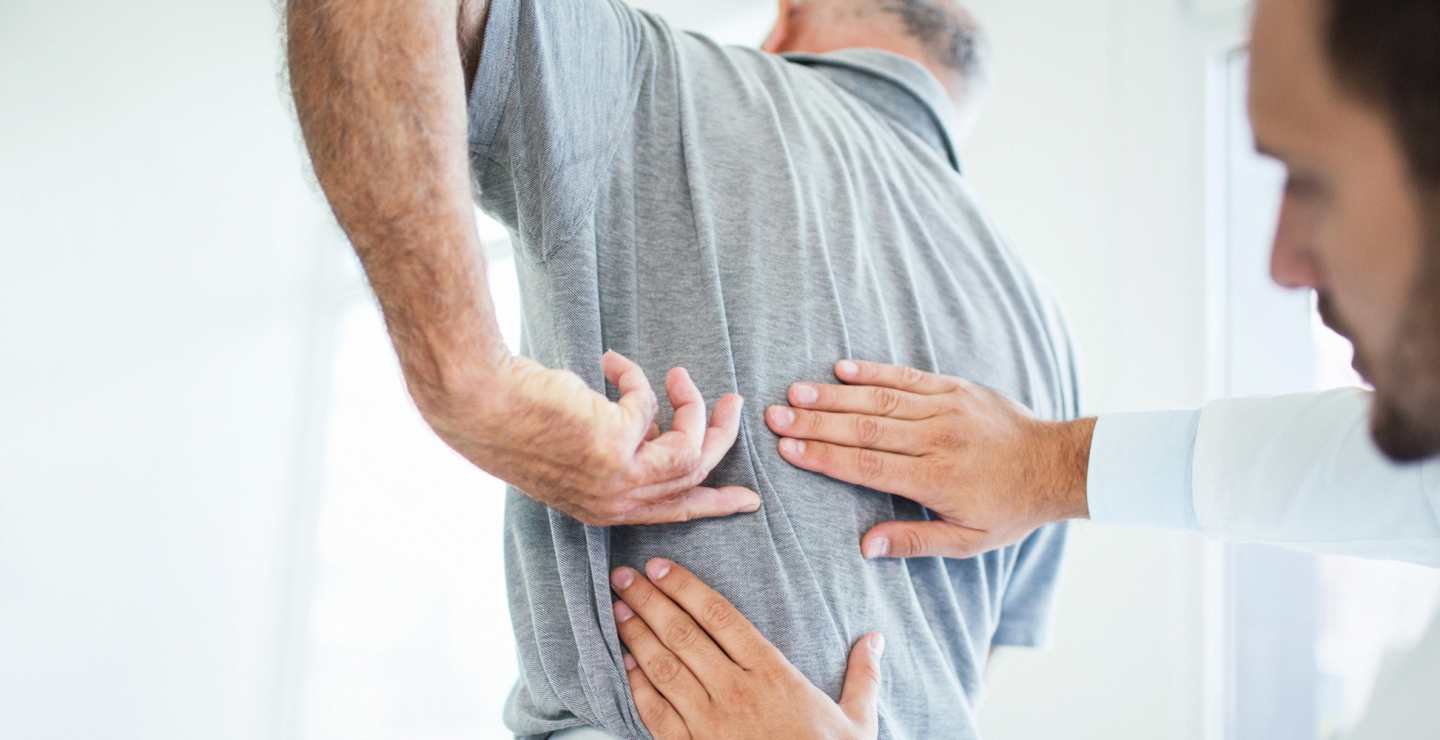 Man showing doctor where his back pain is.