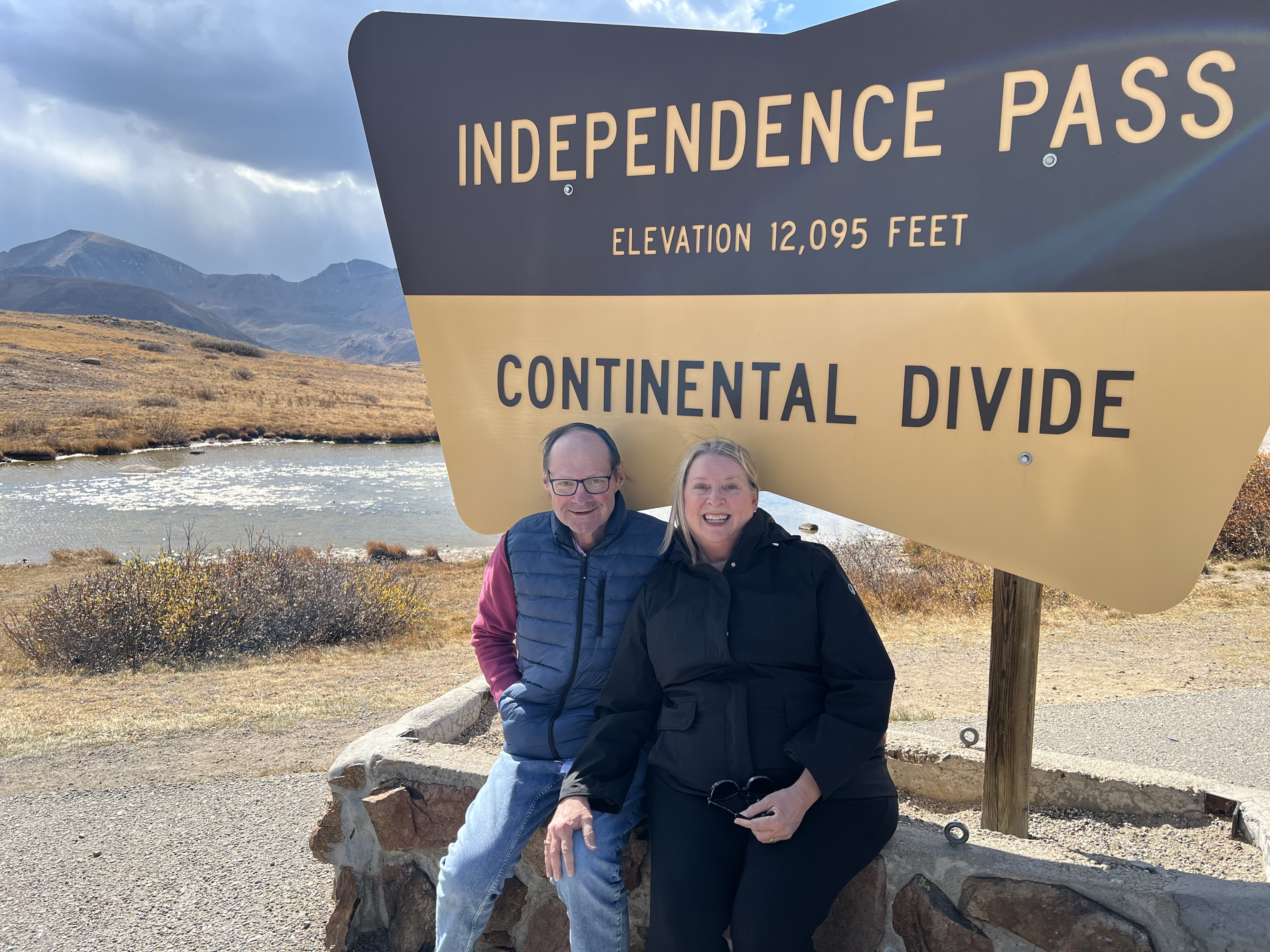 Dana Boucher and his wife sitting in front of a sign. 