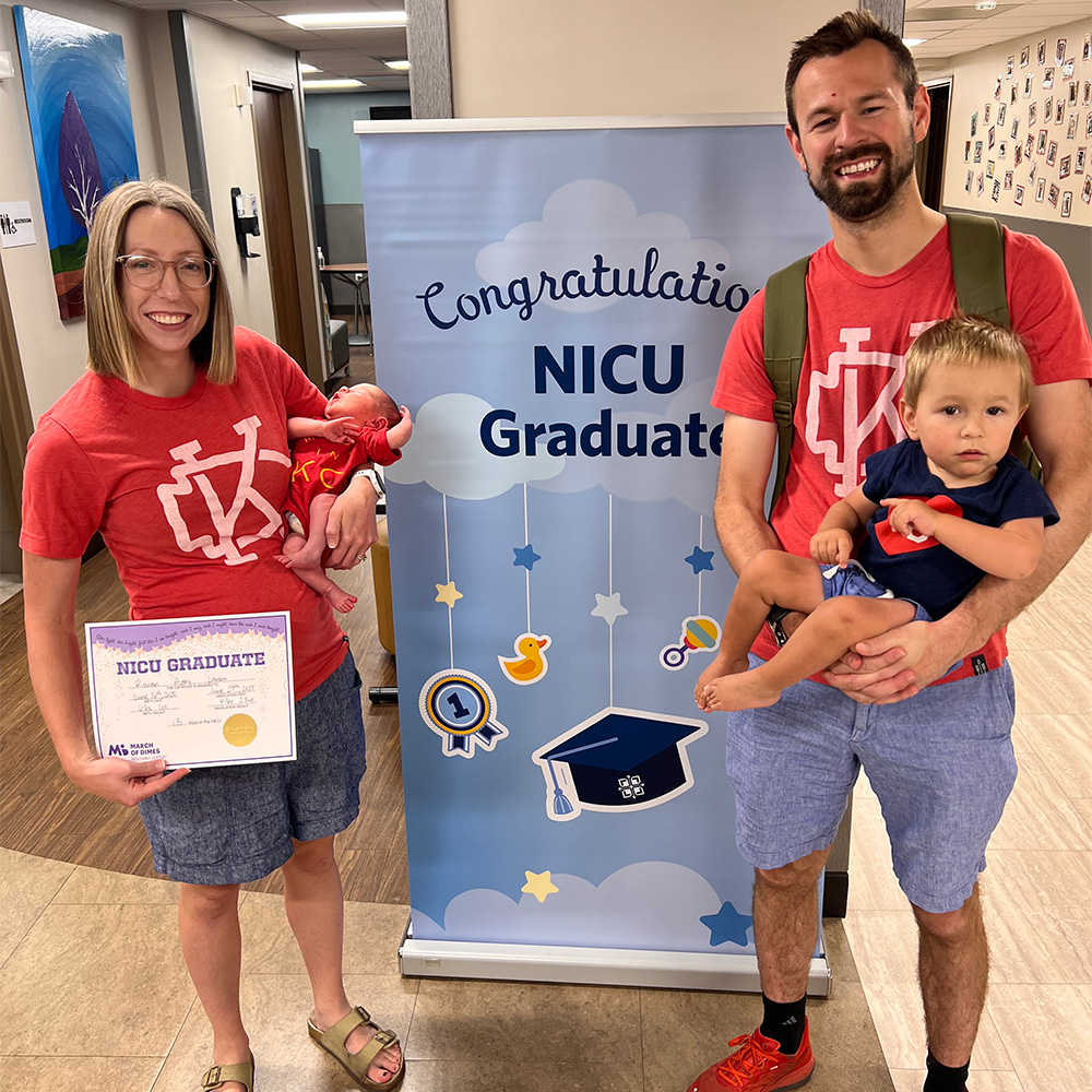 A female patient holding her baby standing next to her husband and toddler.