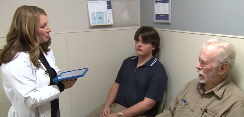 Carl Linck and has grandson is standing in an office talking to a health care provider.