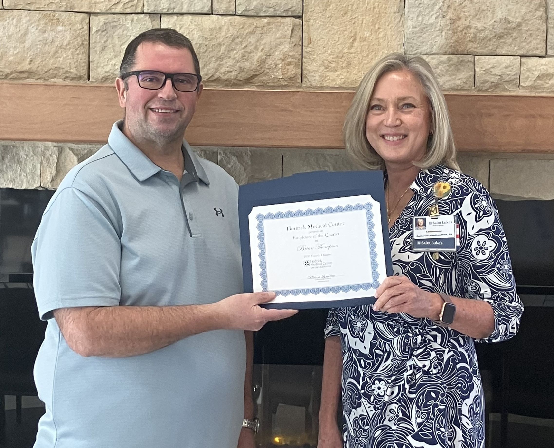 Brian Thompson receives the Hedrick Medical Center Employee of the Quarter Award from Catherine Hamilton. They're both holding the award smiling.