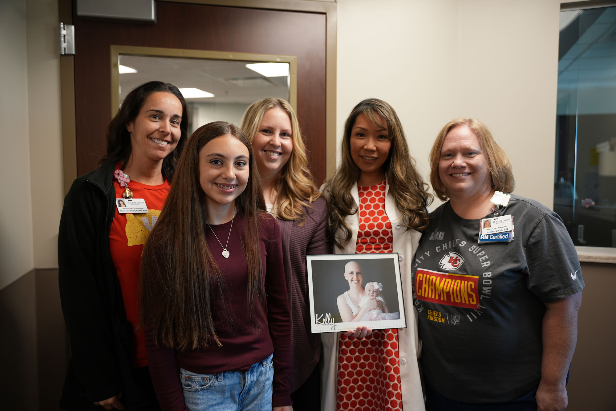 Kelly, a breast cancer patient, stands in a group of smiling providers.