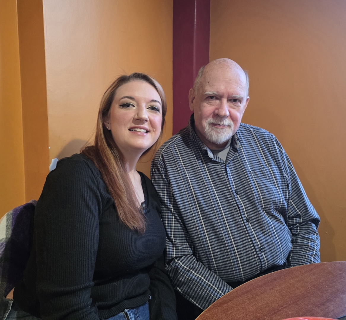 Allison (left) seated near John (right) near a brown wood table