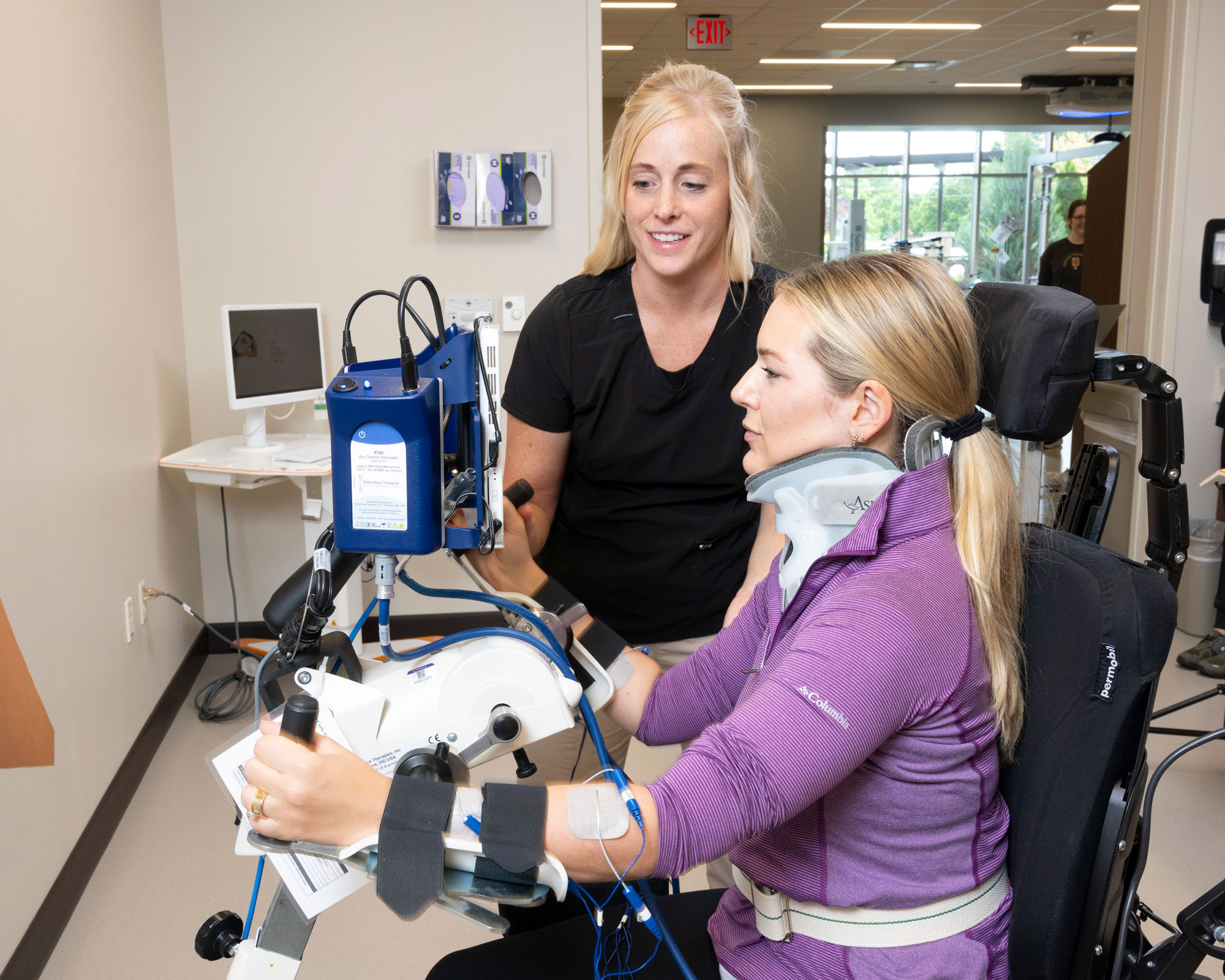 Therapist assists patient during upper extremity cycling therapy